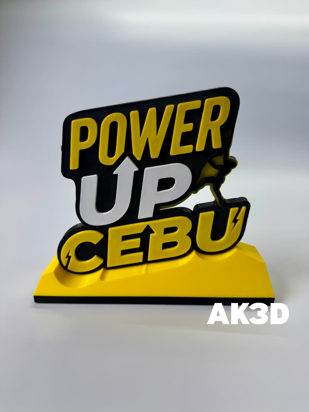Tabletop sign reading POWER UP CEBU in raised yellow, white and black letters on a yellow base