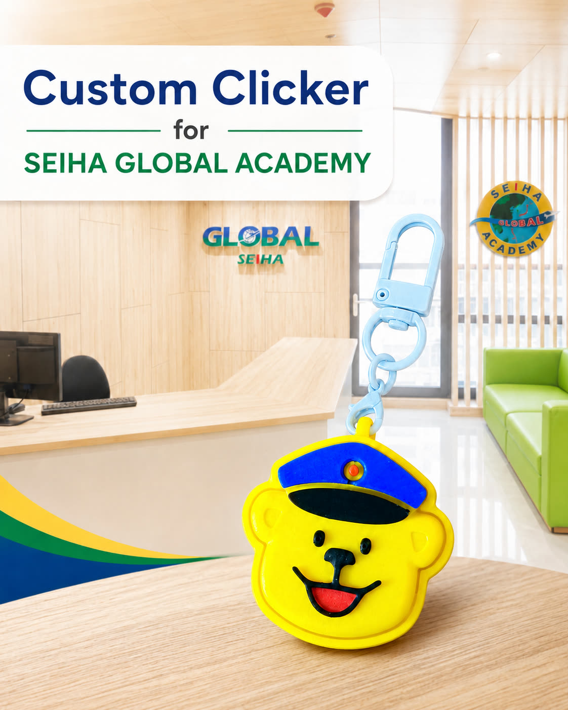 Yellow bear-face clicker keychain wearing a blue cap, standing on a desk in the Seiha Global Academy reception area