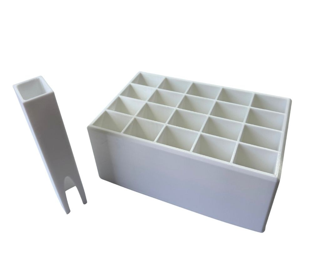 White 3D printed tray with twenty square cells next to a tall square pusher with a notched end